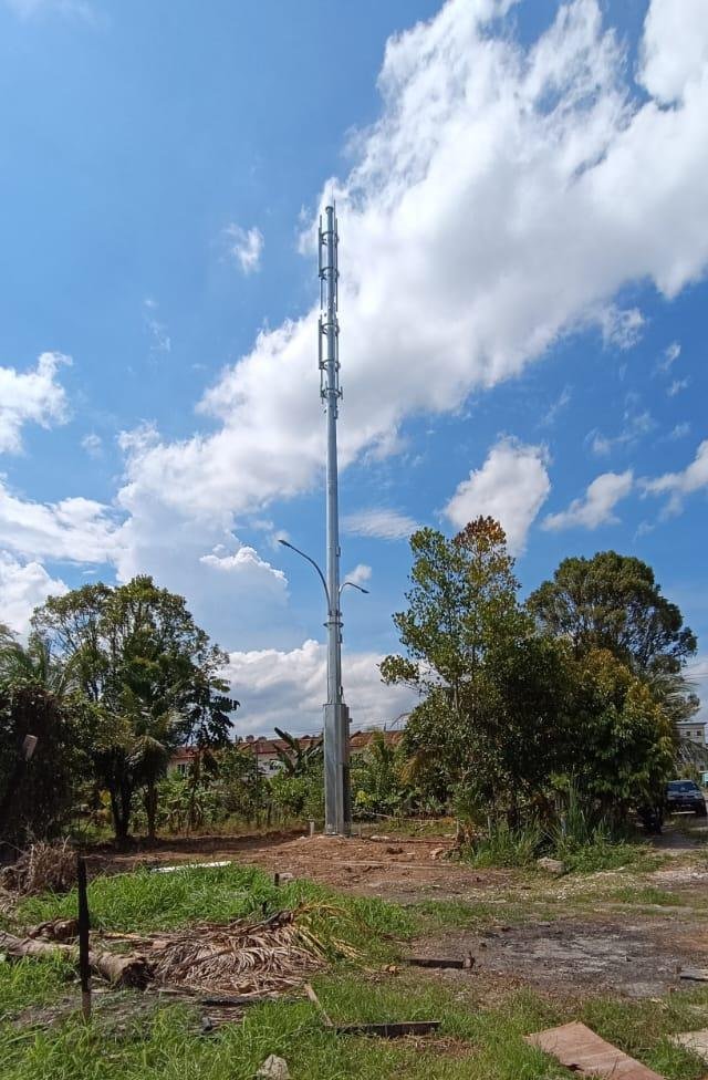 Demanlink smart pole standing against a blue Sarawak sky, carrying 5G antennas